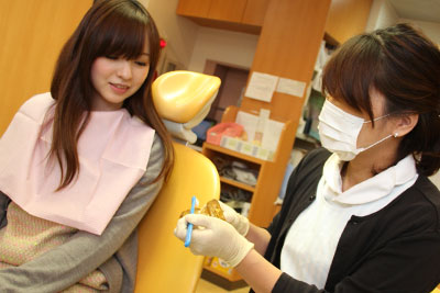 女性歯科衛生士から歯磨き指導を受けている女性
